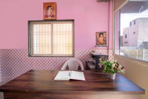 een roze kamer met een houten tafel en een raam bij SPOT ON Shree Gajanan in Aurangabad