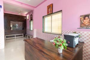 einen Salon mit rosa Wänden und einem Holztisch mit Blumen in der Unterkunft SPOT ON Shree Gajanan in Aurangabad