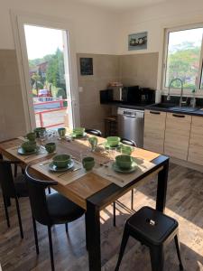 - une cuisine avec une table en bois et des bols verts dans l'établissement Résidence « les Gets » Location T4 Vieux-Boucau-Les-Bains, à Vieux-Boucau-les-Bains