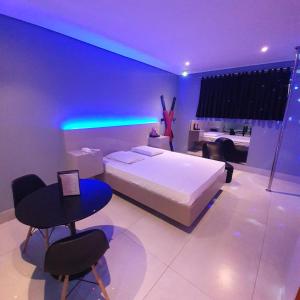um quarto com uma cama branca e iluminação roxa em Desejo Motel em Araçoiaba da Serra