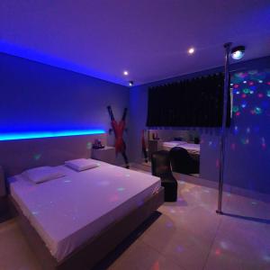 um quarto com uma cama com iluminação azul em Desejo Motel em Araçoiaba da Serra