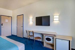 ein Hotelzimmer mit einem Bett und einem Schreibtisch mit einer Mikrowelle in der Unterkunft Motel 6-Grande Prairie, AB in Grande Prairie