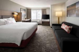 Sonesta Select Seattle Renton Suites في رينتون: غرفه فندقيه بسرير واريكه
