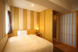 1 dormitorio con cama blanca y ventana en Hotel Sunroute Kumamoto en Kumamoto