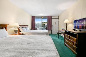 a hotel room with two beds and a flat screen tv at Candlewick Inn and Suites in Eureka Springs