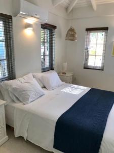 een slaapkamer met een groot wit bed en een blauwe deken bij Villa Perla due (diving villa Chikitu) in Kralendijk