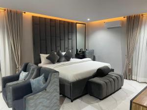 1 Schlafzimmer mit einem großen Bett und 2 Stühlen in der Unterkunft Choice Suites Signature in Ikeja