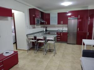 cocina con armarios rojos, mesa y sillas en VV LA ISLA en La Restinga