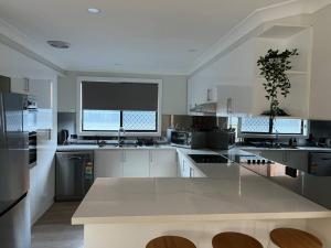 a large white kitchen with a large island in it at Renovated Coastal getaway with water views in Umina