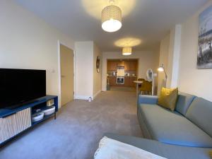 a living room with a blue couch and a flat screen tv at 1 bedroom apartment in the heart of Bournemouth in Bournemouth