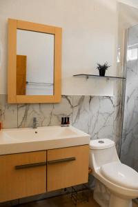 a bathroom with a sink and a toilet and a mirror at Equinoccio Hotel in Santa Ana