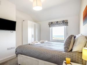 a bedroom with a large bed with a window at Tyn Y Berth in Moelfre