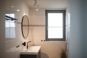 a bathroom with a sink and a mirror and a window at Bheaven I Sea Pilot Premium Apartment in Bremerhaven