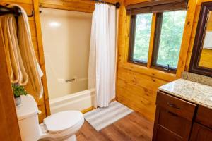 y baño con aseo, bañera y ducha. en Lazy Bear Cabin en Sevierville