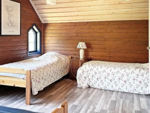 twee bedden in een kamer met houten wanden bij Holiday home ÖRSJÖ in Örsjö