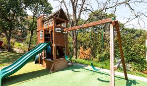 un parco giochi con scivolo e una casetta per i giochi di Woodland Cabins a Santa Ana Jilotzingo