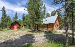 a log cabin with a red barn in the woods at Hooter Hollow by KABINO Fire Pit Big Driveway SmartTV Grill WiFi in Island Park