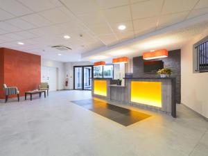 an office lobby with a waiting room with yellow accents at Kyriad Angers Ouest Beaucouzé in Beaucouzé