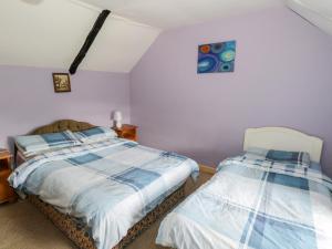 2 letti in una camera da letto con pareti viola di The Thatched Cottage a Liscarney