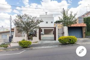 uma casa branca com um portão numa rua em Home Office Curitiba/vaga de estacionamento grátis em Curitiba