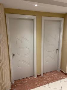 two white doors in a room with at Kreoli Hotel in Athens