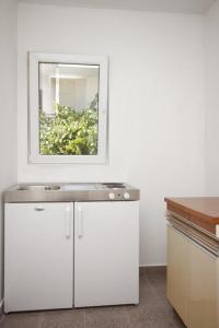 a white kitchen with a sink and a mirror at Double Room Gradac 6819a in Gradac
