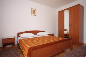 a bedroom with a bed with an orange and orange blanket at Triple Room Metajna 6378d in Metajna