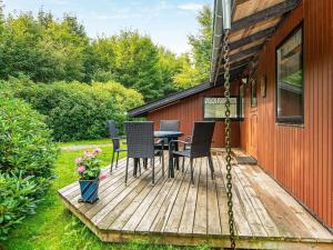 eine Holzterrasse mit Stühlen und einem Tisch auf einem Haus in der Unterkunft 5 person holiday home in Ry in Ry