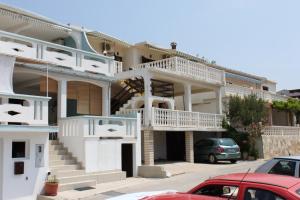 una casa con balcones blancos y coches aparcados en un aparcamiento en Apartment Metajna 6423c en Metajna