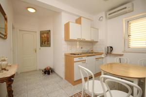 a kitchen with white cabinets and a table and chairs at Apartments and rooms with parking space Baska Voda, Makarska - 6704 in Baška Voda