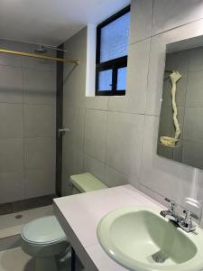 baño con lavabo y aseo y ventana en Alston Inn Hotel, en Quito