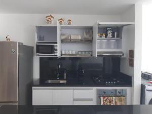 cocina con armarios blancos y encimera negra en Apartamento Santa Marta Bello Horizonte Junto a Olímpica, en Santa Marta