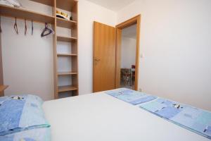 a bedroom with a white bed and a book shelf at Apartment Mandre 6405b in Kolan