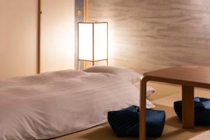 sypialnia z białym łóżkiem i stołem w obiekcie Rinn Niomon w mieście Kioto