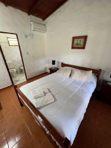a bedroom with a large white bed and a shower at EL PASO IBERA in Colonia Carlos Pellegrini