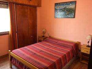 a small bedroom with a bed with a striped blanket at Hernandarias 2 in San Bernardo
