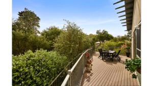 a deck with a table and chairs on a house at Surf Sounds Free Wifi Pet Friendly Outside Only Surf Side in Inverloch