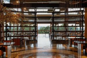 restauracja ze stołami i krzesłami oraz dużymi oknami w obiekcie Mountain Creek Golf Resort & Residences w mieście Si Khio