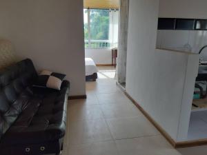 a living room with a black couch and a kitchen at Apartamento pequeño, acogedor, 1 habitación, vista a zonas verdes, English in Calarcá