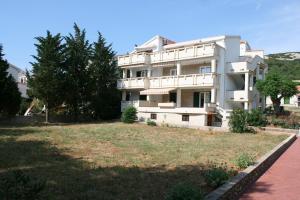 a large white building with a yard in front of it at Apartment Stara Novalja 6375c in Novalja
