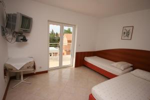 1 Schlafzimmer mit 2 Betten, einem TV und einem Balkon in der Unterkunft Apartment Novalja 6398e in Novalja