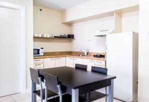 a kitchen with a black table and chairs and a refrigerator at Garden Villa Hotel in Tumon