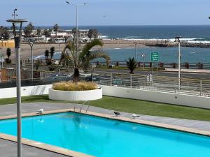a blue swimming pool with the ocean in the background at Departamento frente al mar en Arica in Arica