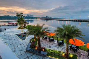 un patio avec des tables et des parasols à côté d'une étendue d'eau dans l'établissement R&F Princess Cove JB By SaffronCasa JB, à Johor Bahru