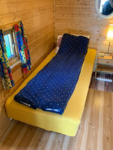 uma cama amarela num quarto com um cobertor azul em Your cabin in Trondheim em Tiller