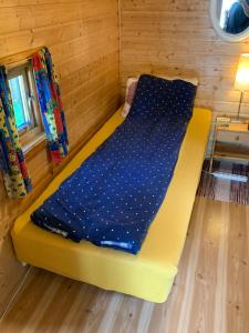 a yellow bed in a room with a blue blanket at Your cabin in Trondheim in Tiller