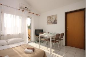 フンタナにあるApartments with a parking space Funtana, Porec - 7076のベッドとテーブルと椅子のある寝室