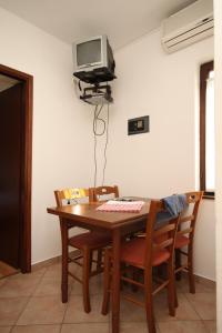 mesa de comedor con sillas y TV en la pared en Apartment Porec 7042b, en Poreč