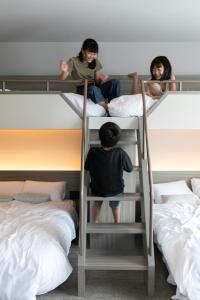 Chłopiec i dziewczynka siedzący na łóżku piętrowym w obiekcie FAV HOTEL HAKODATE w mieście Hakodate