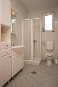 a white bathroom with a shower and a toilet at Apartments with a parking space Novigrad - 7017 in Novigrad Istria